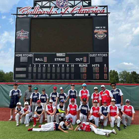 A Tradition team in front of the Ballparks of America scoreboard